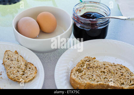 Einfaches Frühstück mit gekochten Eiern, Scheibe Multigrain-Toast und hausgemachter Marmelade. Stockfoto