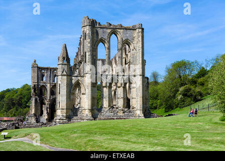 Paar, sitzen auf einer Bank durch die Ruinen von Rievaulx Abbey, in der Nähe von Helmsley, North Yorkshire, England, UK Stockfoto