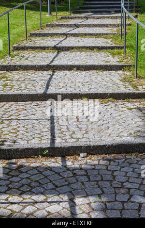 Straße mit Backstein-Steinen mit einer schattenhaften führende Linie Stockfoto
