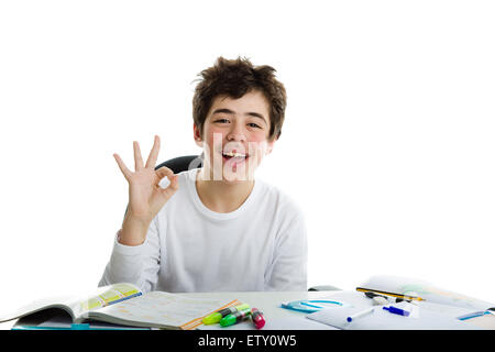 Kaukasische Latein Junge mit Brille sitzt vor den Hausaufgaben, lächelt und fühlt sich glücklich, zeigt "OK", alles in Ordnung, Zeichen Stockfoto