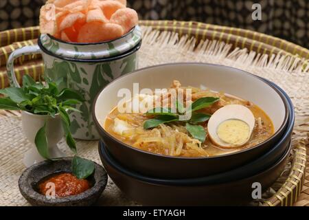 Javanischen vegetarisches Gericht der Reiskuchen in der würzige Kokosnuss Suppe mit Ei, Tofu und Gemüse. Serviert mit knusprigen Kekse. Stockfoto