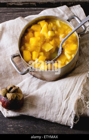 Mango-Chutney oder Marmelade in Vintage Aluminium über alten Holztisch mit ganzen und in Scheiben schneiden Mangostan pan machen. Dunkle, rustikale Atmosphäre Stockfoto