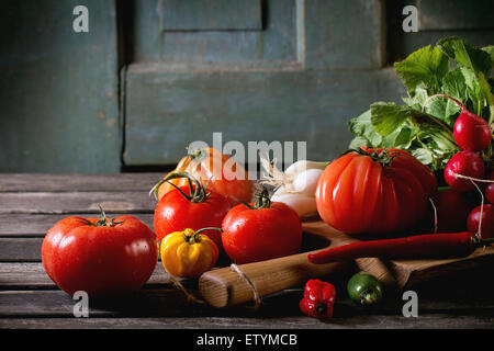 Haufen von Frischgemüse reif bunte Tomaten, Chilischoten, Frühlingszwiebeln und Bündel Radieschen auf Holz hacken an Bord über ol Stockfoto