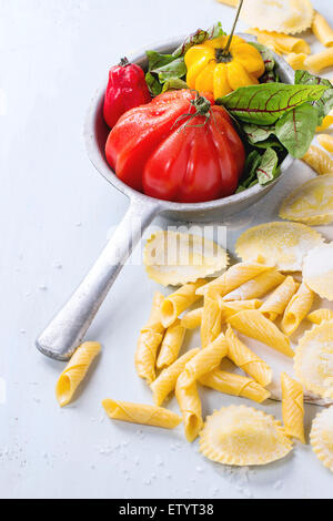 Hausgemachte Ravioli und Garganelli-Nudeln mit Mehl und Vintage Sieb mit Tomate RAF, Salatblätter und gelbe Paprika über Stockfoto