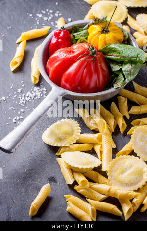 Hausgemachte Ravioli und Garganelli-Nudeln mit Mehl und Vintage Sieb mit Tomate RAF, Salatblätter und gelbe Paprika über Stockfoto