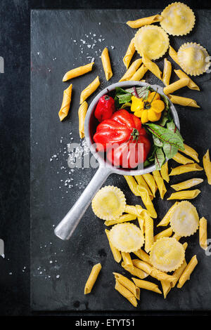 Hausgemachte Ravioli und Garganelli-Nudeln mit Mehl und Vintage Sieb mit Tomate RAF, Salatblätter und gelbe Paprika über Stockfoto