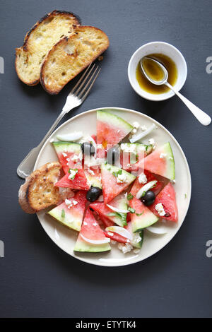 Wassermelonen-Salat mit Feta-Käse, schwarze Oliven, Zwiebeln und Basilikum Stockfoto