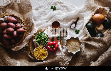 Verschiedene Gemüse, einschließlich rote Kartoffeln, Frühling Erbsen, Mais, Avocados, Zwiebeln und Knoblauch sind auf einer weißen Farm-Stil angezeigt. Stockfoto