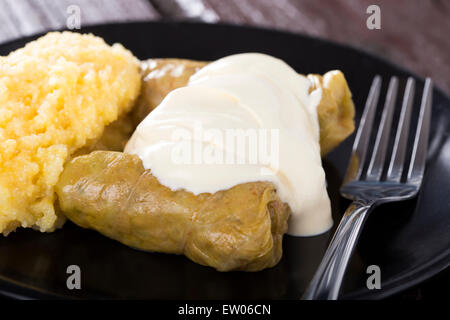 Kohlrouladen mit Hackfleisch und Reis gefüllt auf Teller mit Polenta, über Holztisch Stockfoto