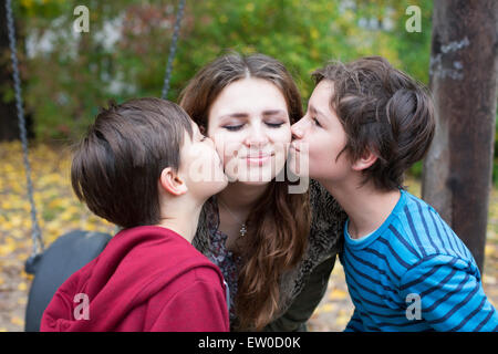 zwei jungen, die ein junges Mädchen auf ihren Wangen küssen Stockfoto