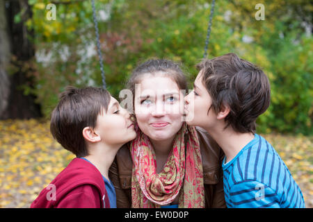 zwei jungen, die ein junges Mädchen auf ihren Wangen küssen Stockfoto