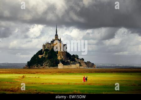 Normandie Frankreich. Le Mont Saint-Michel. Osten über die Gezeiten Bucht Salzmarsch. Mann Frau Hundewiesen im Abendlicht Stockfoto