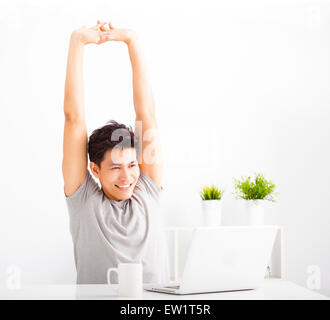 entspannte junge Mann beobachtet Laptop im Wohnzimmer Stockfoto