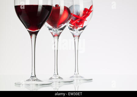 Weingläser mit roten Wein, Herz und Golf Ball auf weißen Tisch Stockfoto