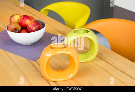 Schale mit roten Äpfeln und zwei bunte Vasen auf einem Holztisch Stockfoto