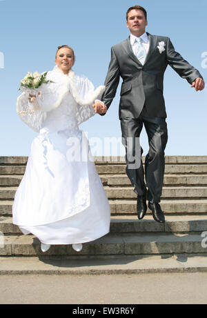 Mann und Braut gegen blauen Himmel springen Stockfoto