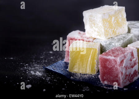 Turkish Delight Stücke auf blauem Papierserviette auf schwarzem Hintergrund Stockfoto