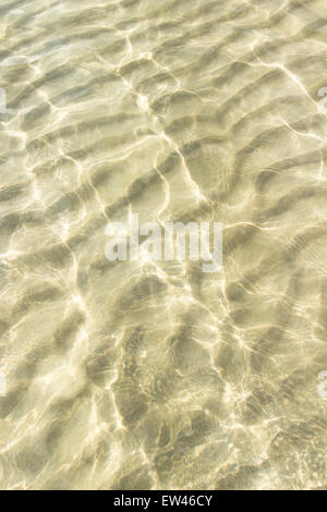transparentes Wasser plätschern, Sand Wellen und Sonnenlicht blendet. Meer-Tiefpunkt-Muster Stockfoto