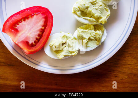 Die Hälfte der Roma-Tomaten auf einem Teller mit deviled Eiern. Stockfoto