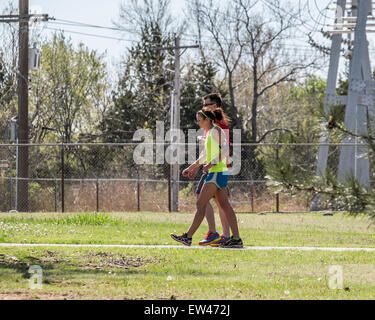 Ein junges Paar der kaukasischen in Ausübung Kleidung, die Frau mit einem Schrittzähler auf ihrem Arm, gehen die Wege am Lake Hefner, Oklahoma City, Oklahoma, USA. Stockfoto