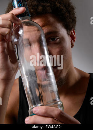 Ein junger Mann mit einer leeren Flasche Alkohol. Stockfoto