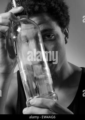 Ein junger Mann mit einer leeren Flasche Alkohol. Stockfoto