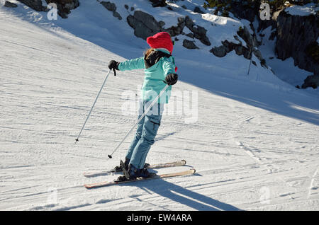 Eine Skifahrer-Girl ist auf der Piste von verdichtetem Schnee rutschen. Stockfoto