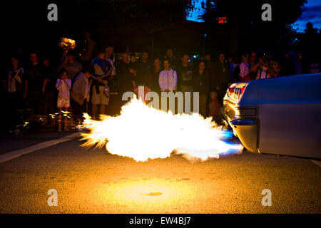 Zuschauer stehen entlang einer Straße, die gerade eines Oldtimers mit einem flammenden Auspuff in Coeur d ' Alene, Idaho. Stockfoto