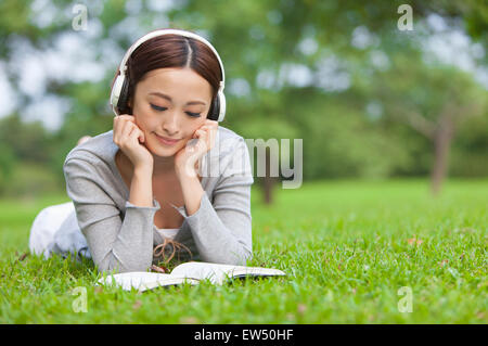 Junge Frau, ein Buch lesen und Musik hören Stockfoto