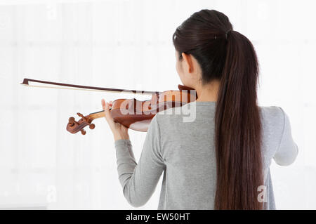 Junge Frau spielt Geige mit Rückansicht Stockfoto