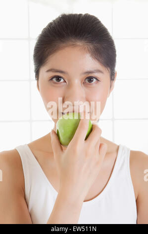 Junge Frau hält einen Apfel und lächelt in die Kamera Stockfoto