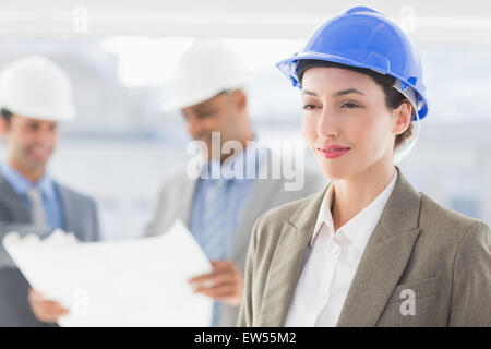 Geschäftsleute und eine Frau mit harten Hüte und Holding Blaupause Stockfoto