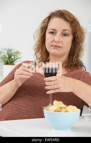 Frau rauchen Zigaretten und trinken Wein und Essen Snacks Stockfoto