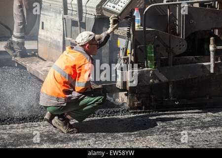 Sankt-Petersburg, Russland-30. Mai 2015: Männer bei der Arbeit, städtische Straße ist im Bau, Betreiber des Fertigers Maschine Stockfoto