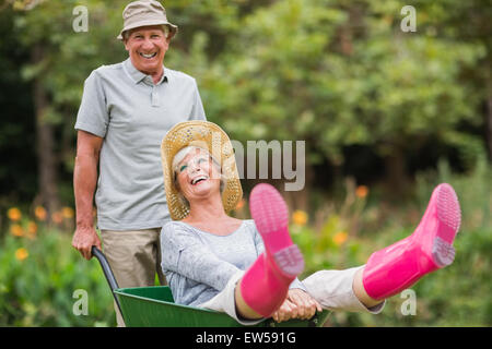 Gerne älteres Paar spielen mit einer Schubkarre Stockfoto