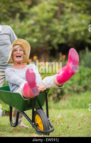 Gerne älteres Paar spielen mit einer Schubkarre Stockfoto