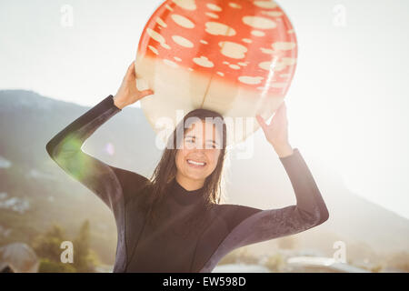 Frau im Neoprenanzug mit einem Surfbrett an einem sonnigen Tag Stockfoto