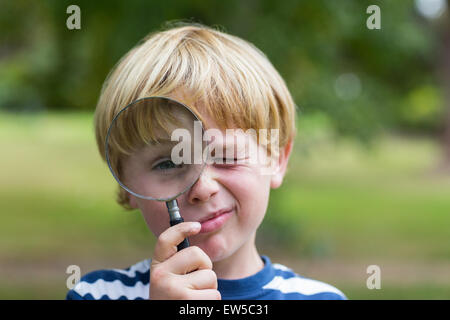 Neugieriger kleiner Junge Blick durch die Lupe Stockfoto