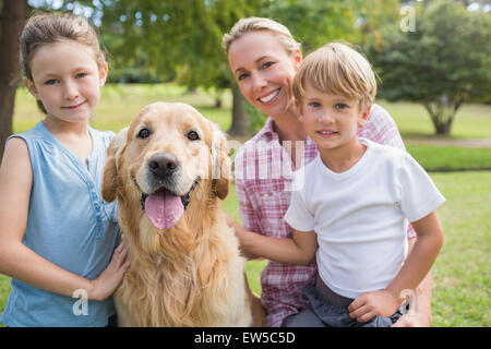 Glückliche Familie Blick in die Kamera und spielen mit ihrem Hund Stockfoto