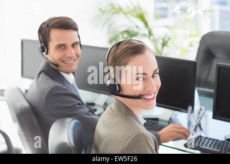 Geschäftsleute mit Headsets, die mit dem Computer Stockfoto