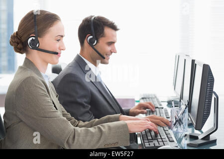 Geschäftsleute mit Headsets, die mit dem Computer Stockfoto