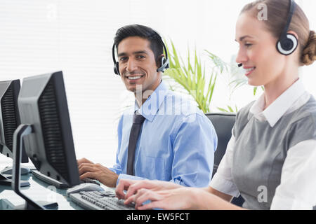 Geschäftsleute mit Headsets, die mit dem Computer Stockfoto