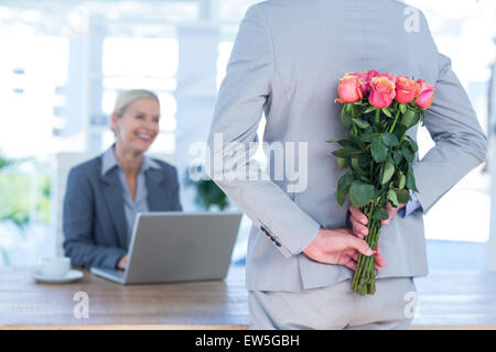 Geschäftsmann versteckt Blumen hinter Rücken für Kollegen Stockfoto