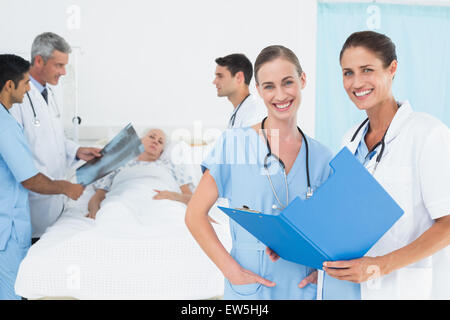 Bericht lesen, mit Kollegen und Patienten hinter Stockfoto