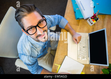 Lässige Geschäftsmann Notizen in seinem Notizblock und lächelt in die Kamera Stockfoto