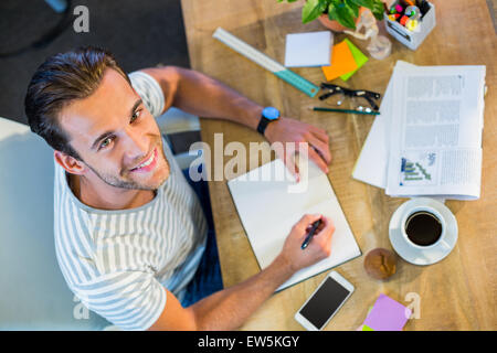 Lächelnde lässige Geschäftsmann in Notepad schreiben Stockfoto