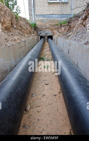neue moderne Kunststofftechnik schwarz Heizungsrohre im Graben in der Nähe von Stadthaus Stockfoto