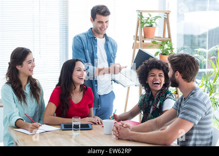 Junger Geschäftsmann mit seinem Laptop an Kollegen Stockfoto