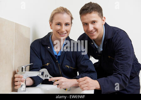 Weiblichen Auszubildenden Klempner Arbeiten am Wasserhahn im Badezimmer Stockfoto