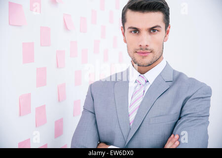 Hübscher junger Geschäftsmann im Anzug im Büro stehen und Blick in die Kamera Stockfoto